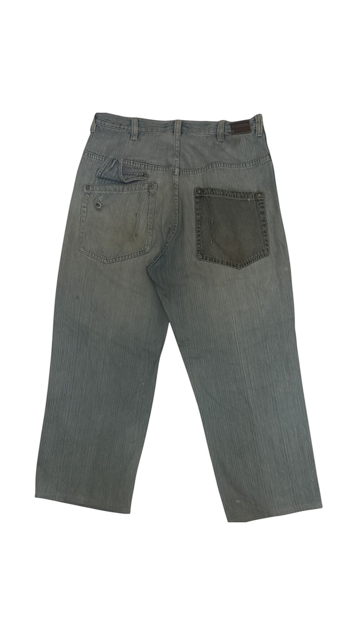 SohoStich Co. distressed faded blue denim jeans with dark grey patchwork on left thigh and paint splatters.